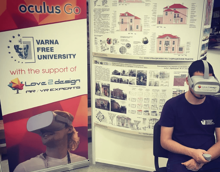 Посетител с Oculus Go VR очила разглежда виртуална обиколка на университета пред архитектурни постери