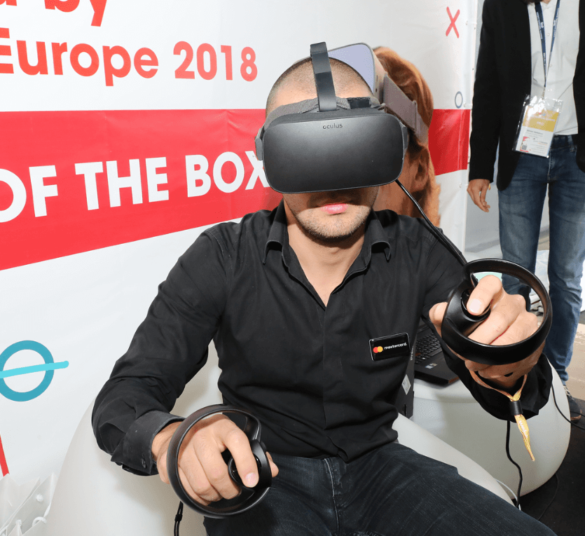 Мъж използва Oculus Rift и контролери за пълноценна виртуална реалност по време на изложение